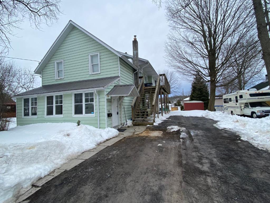 a green house with a driveway in the snow at The Water Street Inn in Napanee