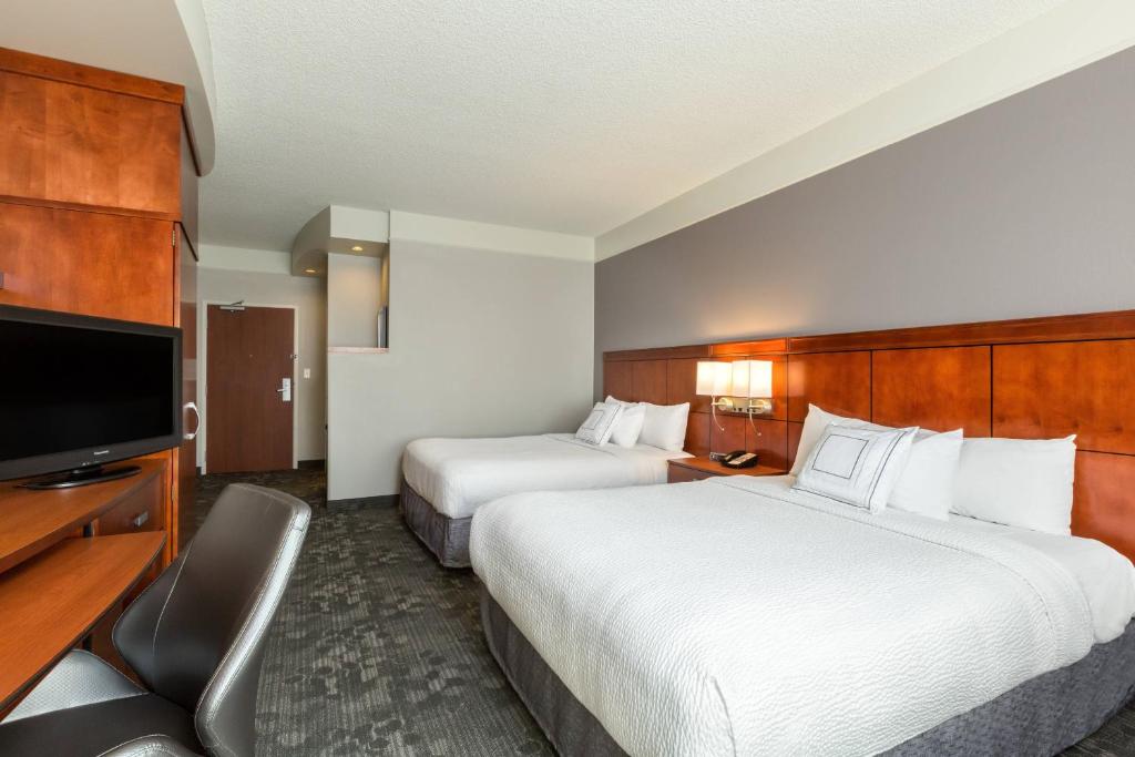 a hotel room with two beds and a flat screen tv at Courtyard by Marriott Houston Galleria in Houston