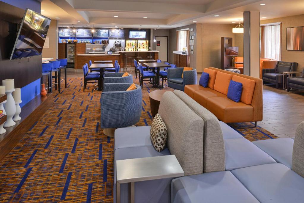 a hotel lobby with couches and chairs and a bar at Courtyard Atlanta Suwanee in Suwanee