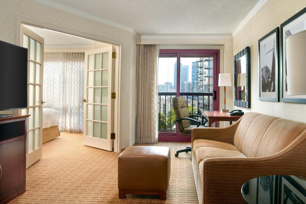 Atlanta Marriott Suites Midtown في أتلانتا: غرفة معيشة مع أريكة وغرفة مطلة