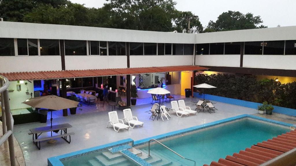Pacific Coast Hotel في قرية بلايا بونيتا: مسبح وكراسي ومظلات بجانب مبنى