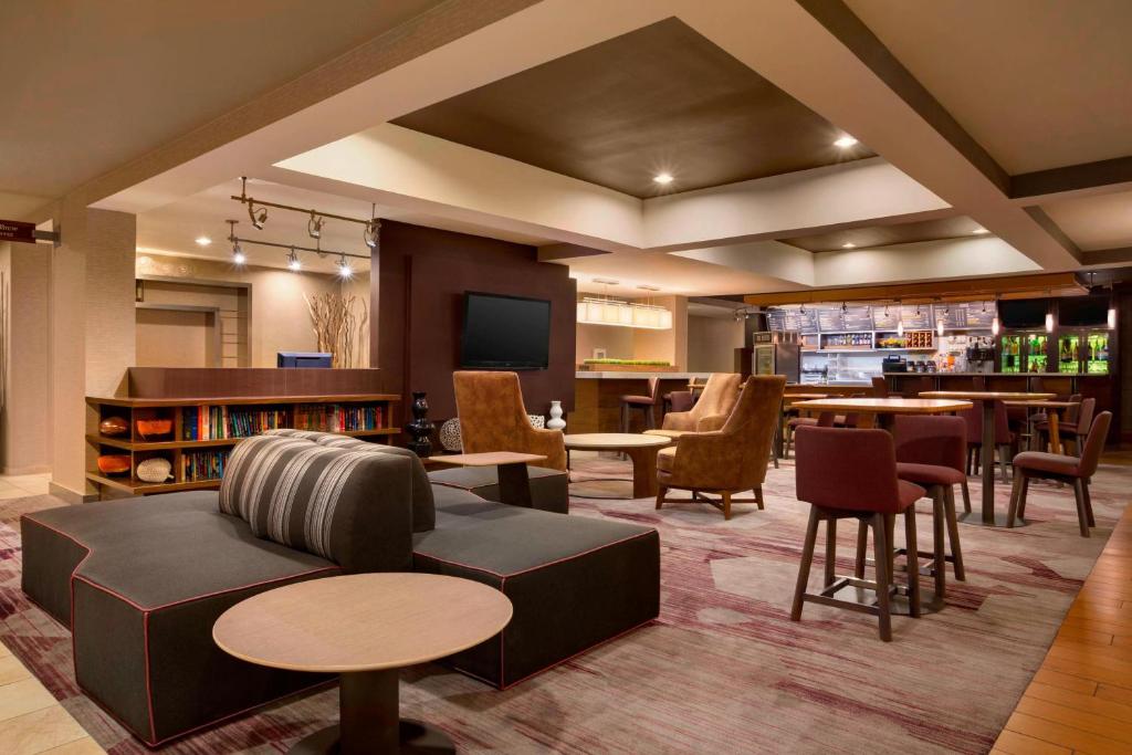 a lobby with a couch and tables and a bar at Courtyard by Marriott Champaign in Champaign