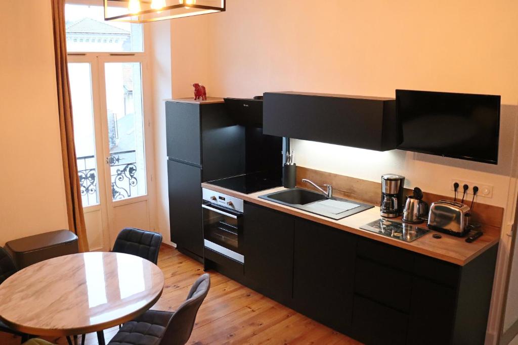 - une cuisine avec un évier et un comptoir avec une table dans l'établissement Appartement 2/4 pers Vacance-Cure cosy et ensoleillé, à La Bourboule
