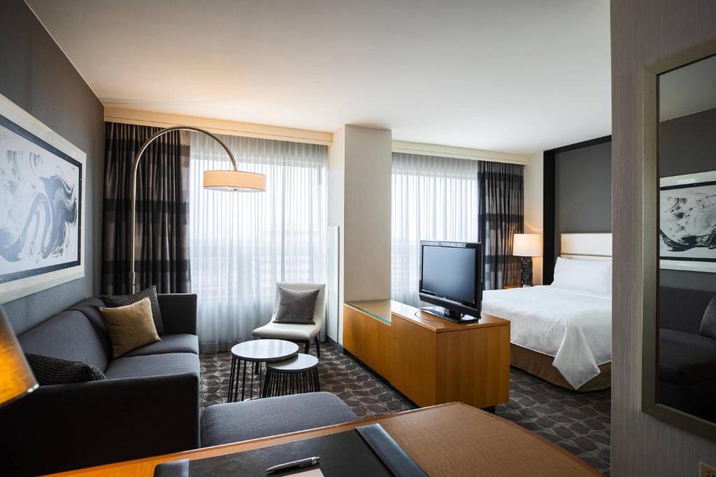 a hotel room with a bed and a television at Renaissance Chicago O'Hare Suites Hotel in Rosemont