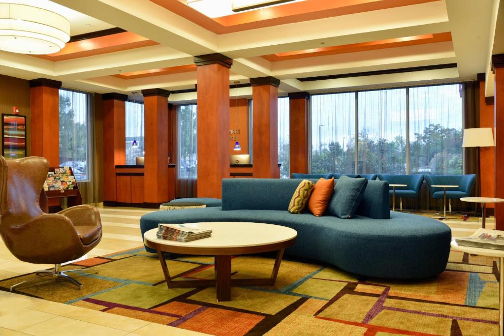 a lobby with a blue couch and a table and chairs at Fairfield Inn Hartford Airport in Windsor Locks