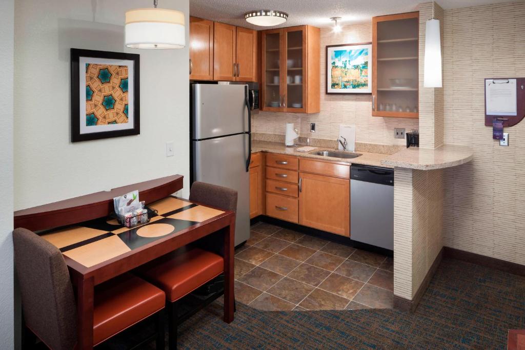 a kitchen with a table and a refrigerator at Residence Inn by Marriott Hattiesburg in Hattiesburg