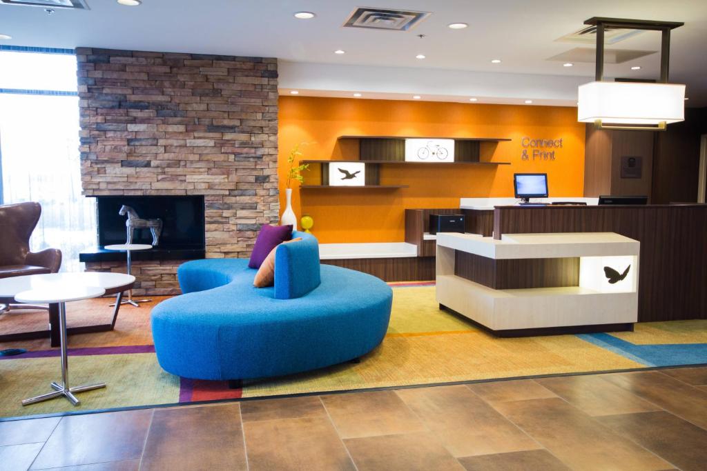 Fairfield Inn & Suites by Marriott Denver Northeast/Brighton في برايتون: غرفة معيشة مع كرسي أزرق ومدفأة
