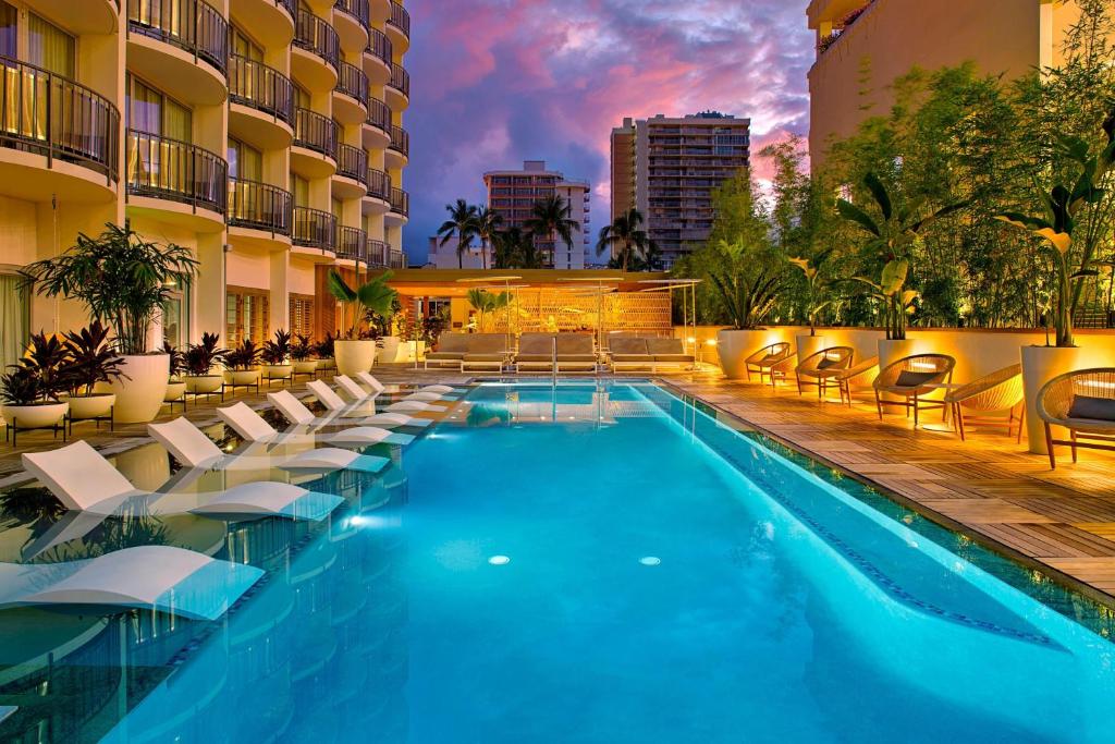 a swimming pool with lounge chairs and a hotel at The Laylow, Autograph Collection in Honolulu