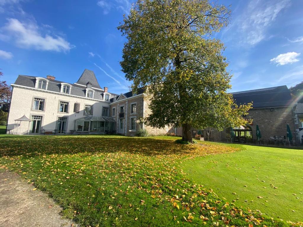 a large white house with a tree in the yard at La chambre et le studio du château du golf de Bernalmont in Liège
