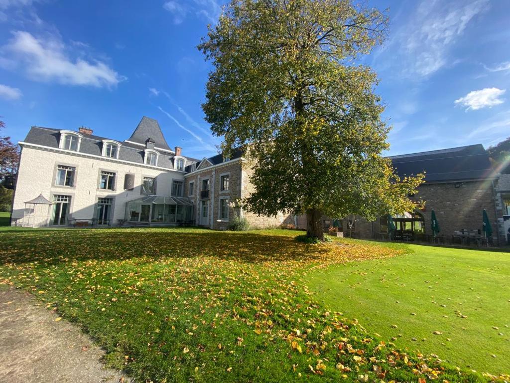 une grande maison blanche avec un arbre dans la cour dans l'établissement La chambre et le studio du château du golf de Bernalmont, à Liège
