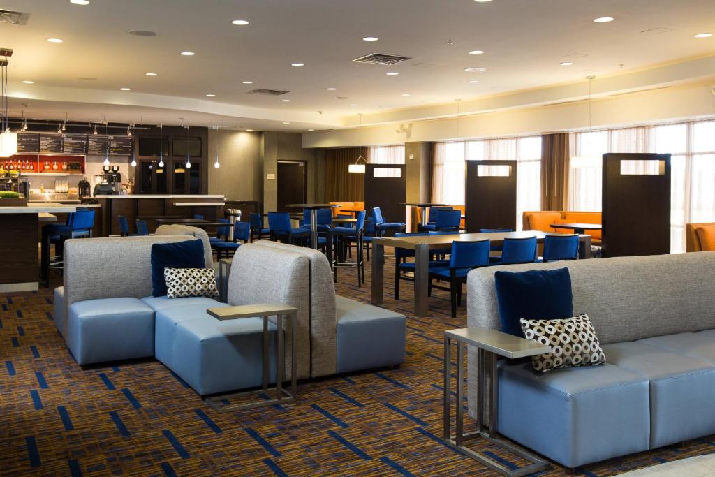 a restaurant with couches and tables and blue chairs at Courtyard by Marriott Winchester Medical Center in Winchester