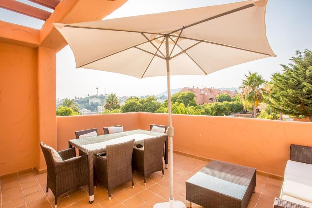 a table and chairs with an umbrella on a balcony at Los Lagos de Santa Maria Golf in Marbella