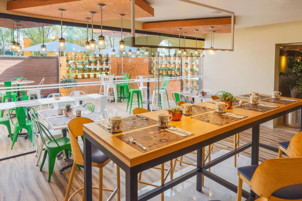 un restaurante con mesas de madera y sillas verdes en Courtyard Toluca Airport en Toluca
