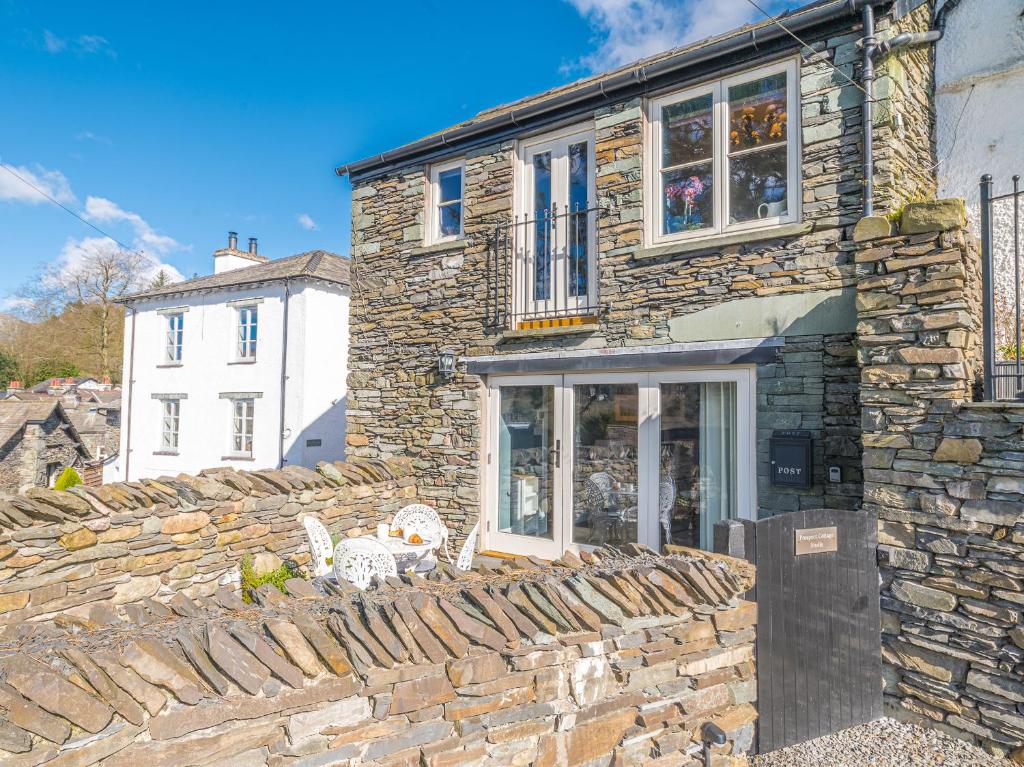 a stone house with two chairs on a stone wall at Prospect Cottage Studio in Ambleside