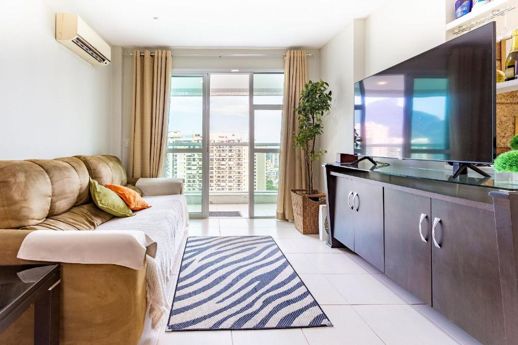 een woonkamer met een bank en een flatscreen-tv bij Confortável apto 2Qtos c/ Varanda e Vista Mar in Rio de Janeiro