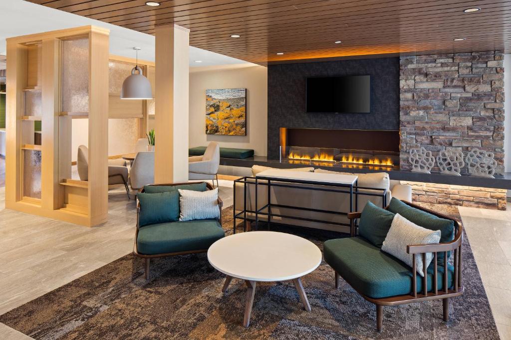 a lobby with a fireplace and chairs and a table at Fairfield by Marriott Inn & Suites Duluth in Duluth