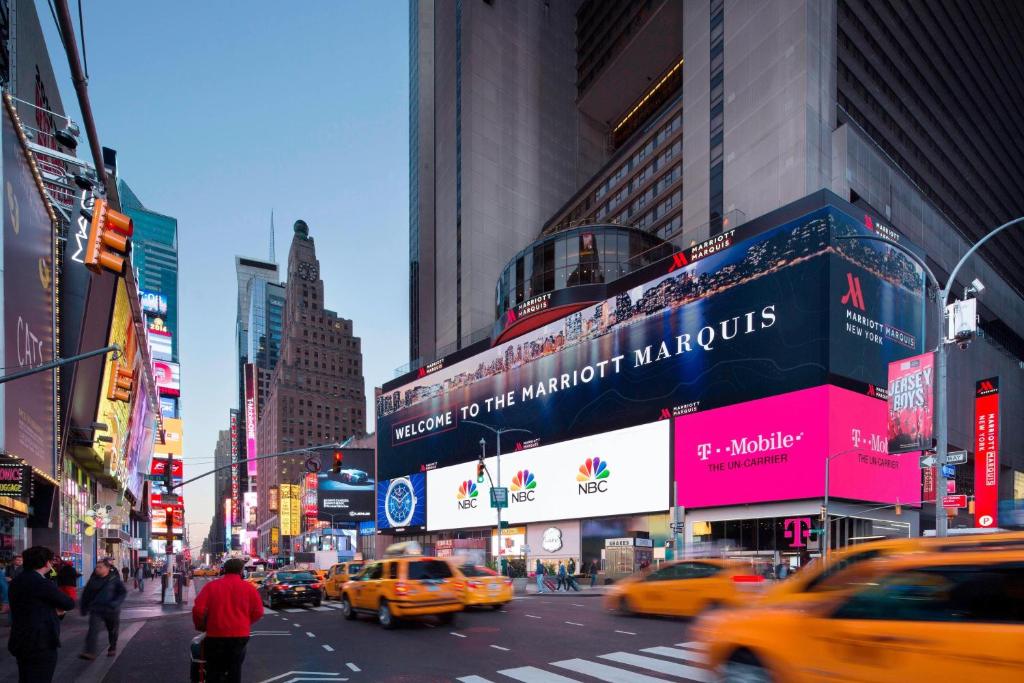una trafficata strada cittadina con taxi, pedoni ed edifici di New York Marriott Marquis a New York