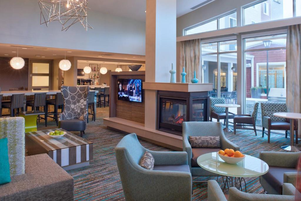 a hotel lobby with a fireplace and a dining area at Residence Inn by Marriott Chicago Bolingbrook in Bolingbrook