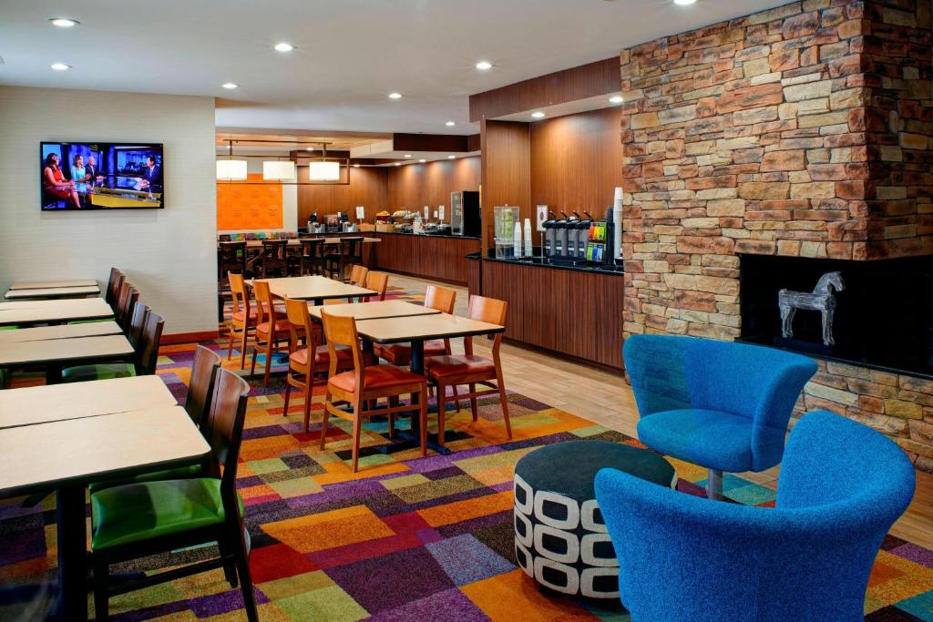 a restaurant with tables and chairs and a fireplace at Fairfield Inn & Suites Detroit Farmington Hills in Farmington Hills