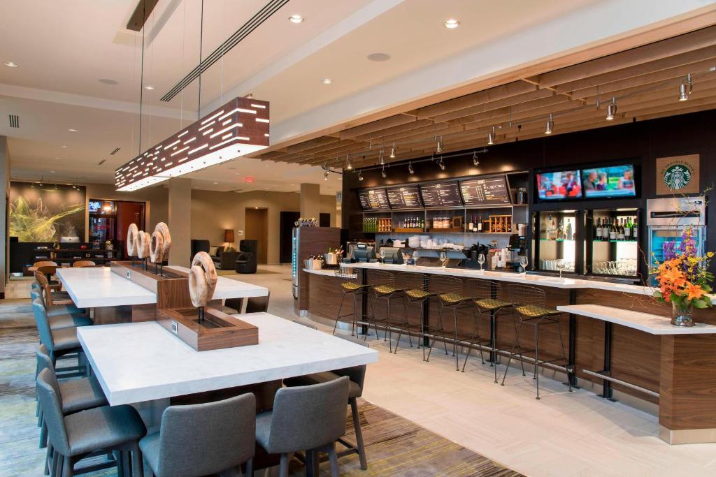 a restaurant with tables and chairs and a bar at Courtyard by Marriott Holland Downtown in Holland