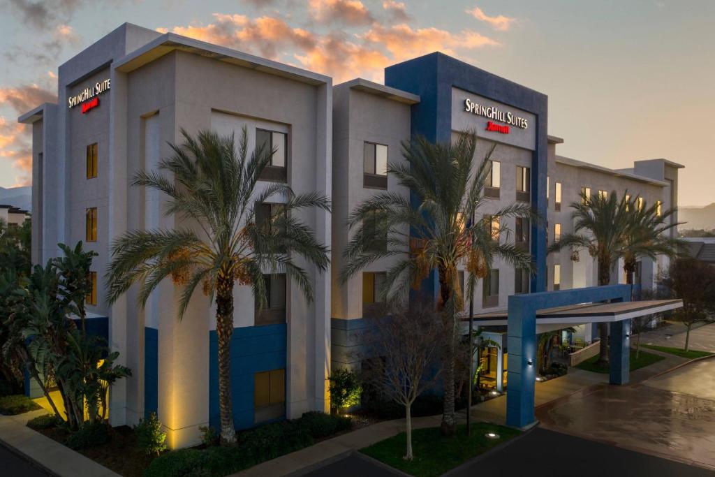 a hotel with palm trees in front of a building at SpringHill Suites by Marriott Corona Riverside in Corona