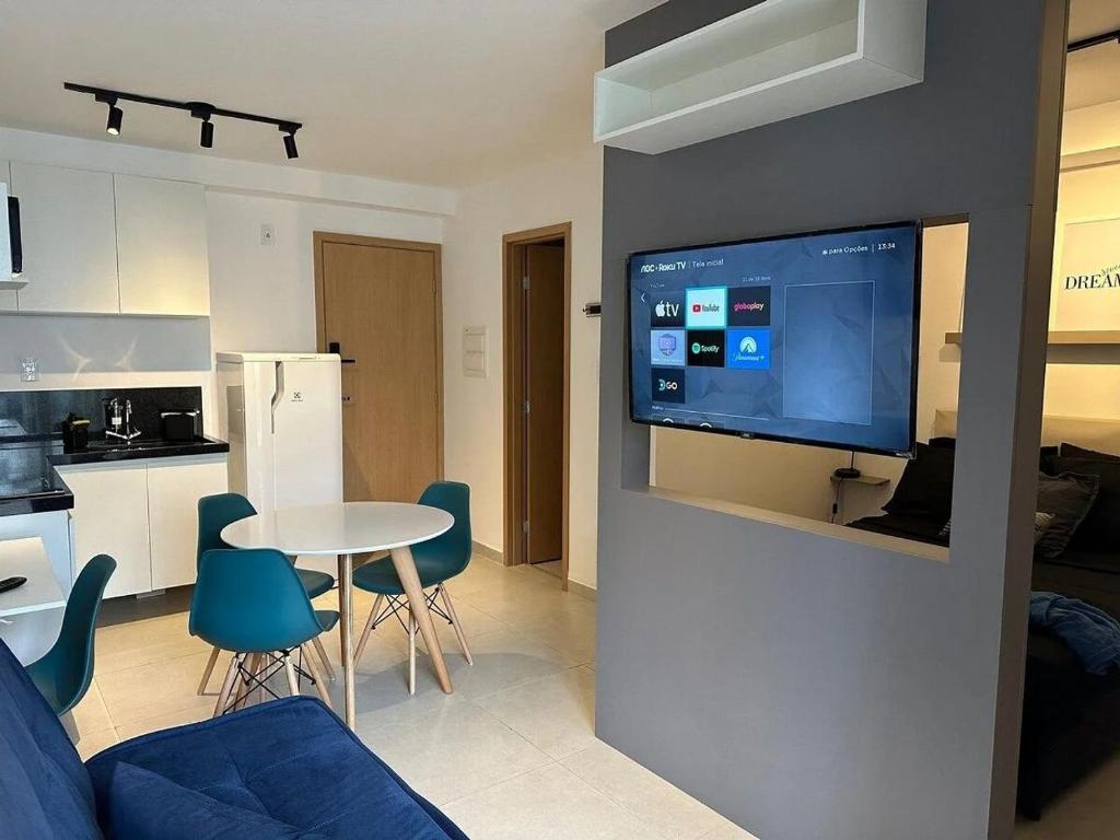 uma sala de estar com uma mesa e uma televisão na parede em Studio Felicittá piscina cozinha academia em Juiz de Fora