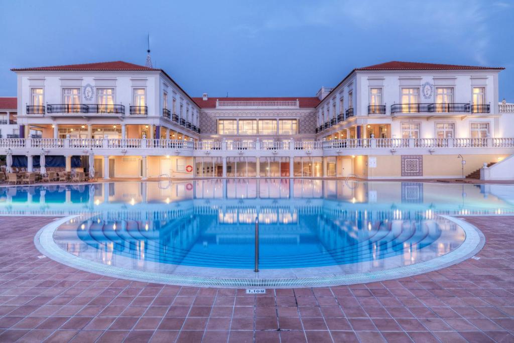 un hôtel avec une piscine en face d'un bâtiment dans l'établissement Praia D'El Rey Marriott Golf & Beach Resort, à Casal da Lagoa Seca