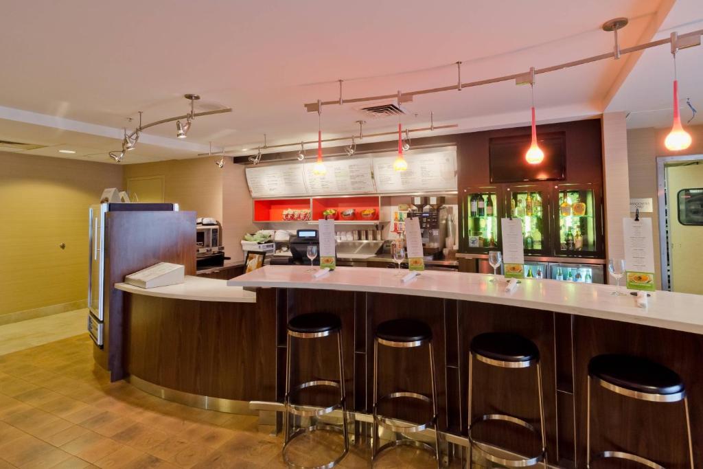 a kitchen with a bar with stools and a refrigerator at Courtyard Salt Lake City Layton in Layton