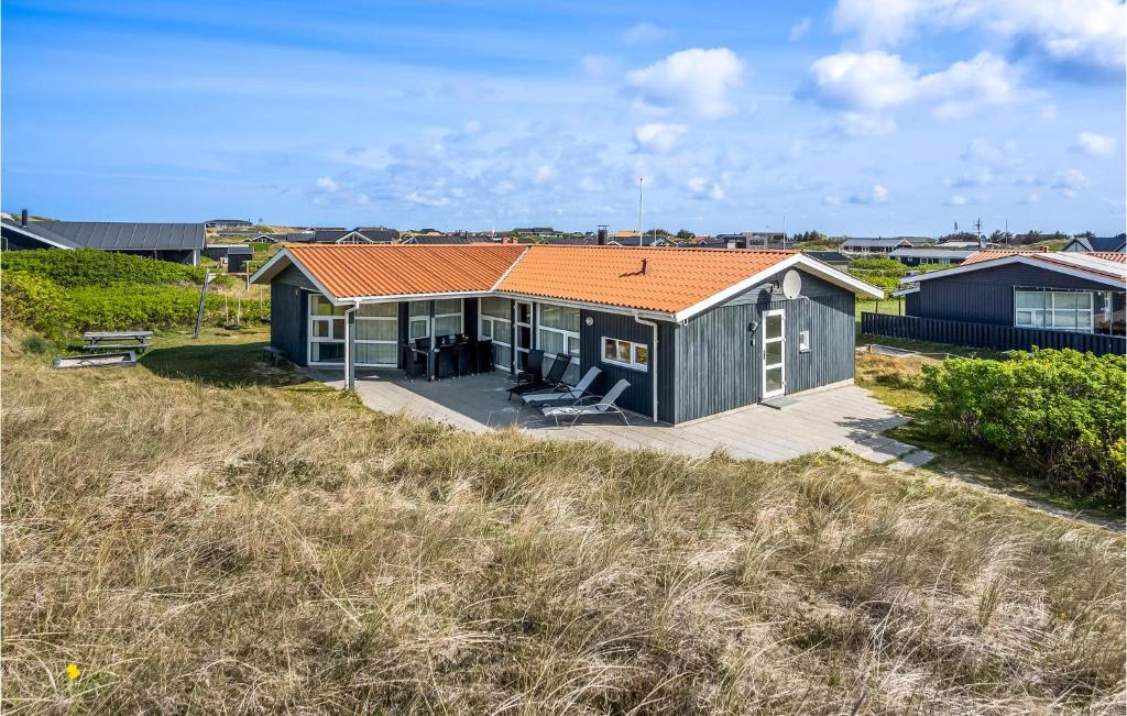 ヴィデ・サンデにあるNice Home In Hvide Sande With 4 Bedrooms, Sauna And Indoor Swimming Poolの畑の上にオレンジ色の屋根がある家