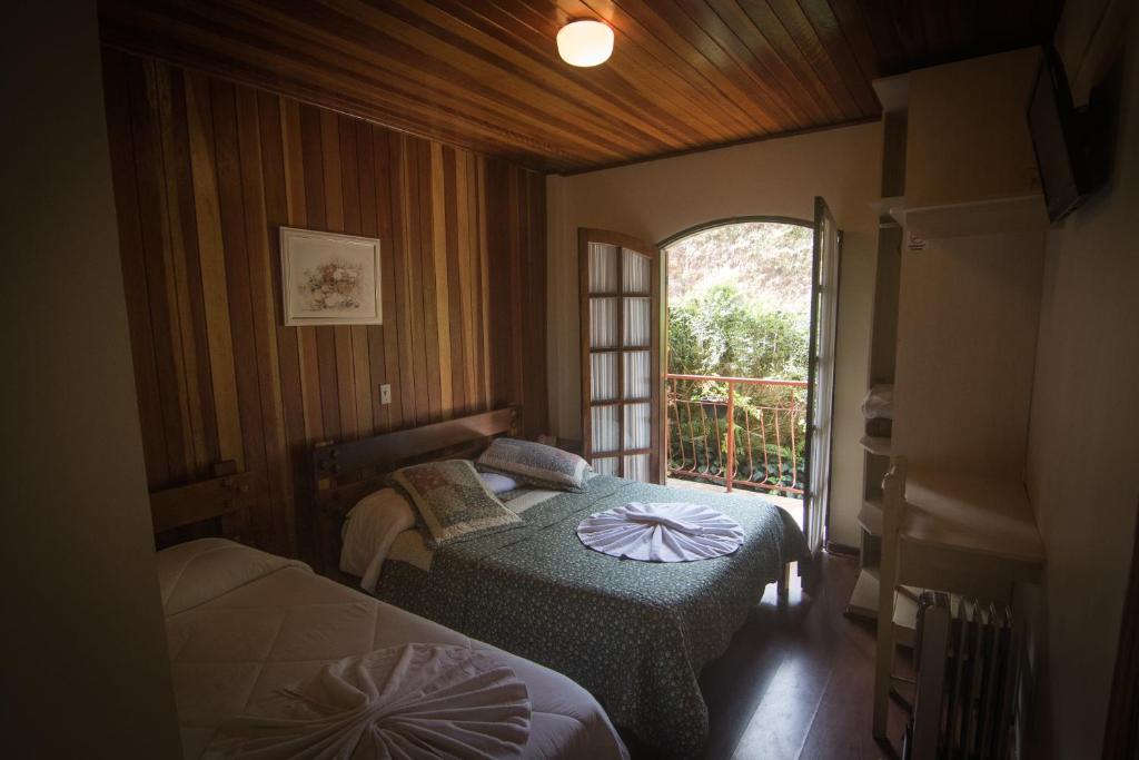a small room with two beds and a window at Hotel Vill' Agi in Campos do Jordão