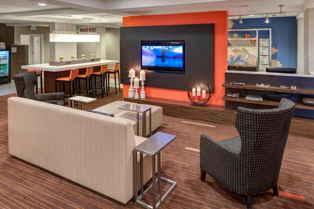 a lobby with chairs and a tv and a bar at Courtyard by Marriott Wichita East in Wichita