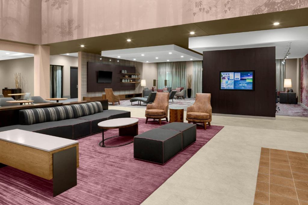 a lobby with a couch and chairs and a flat screen tv at Courtyard by Marriott Dallas Flower Mound in Flower Mound