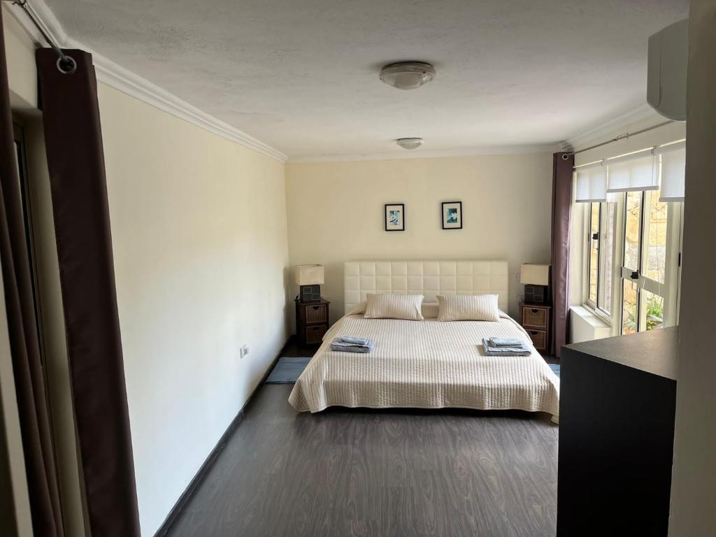 a bedroom with a bed and a large window at Groundfloor Maisonette By The Seaside in St Paul's Bay