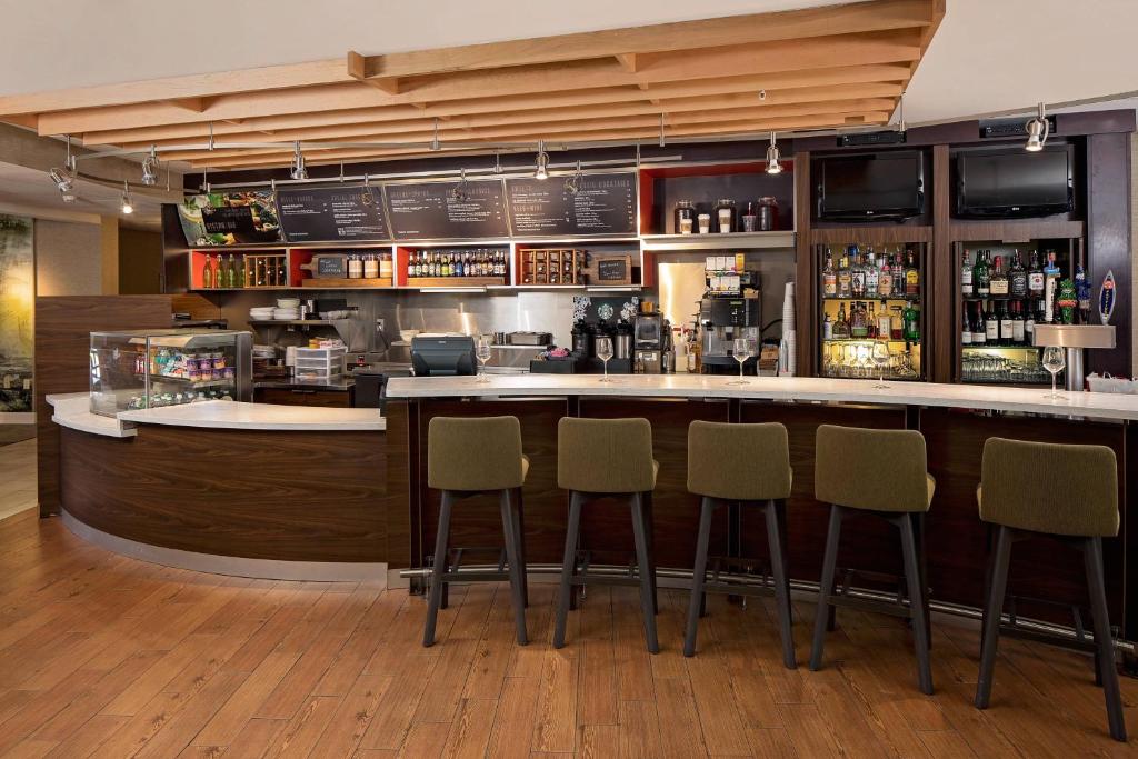 a bar with four chairs in a restaurant at Courtyard Long Island MacArthur Airport in Ronkonkoma