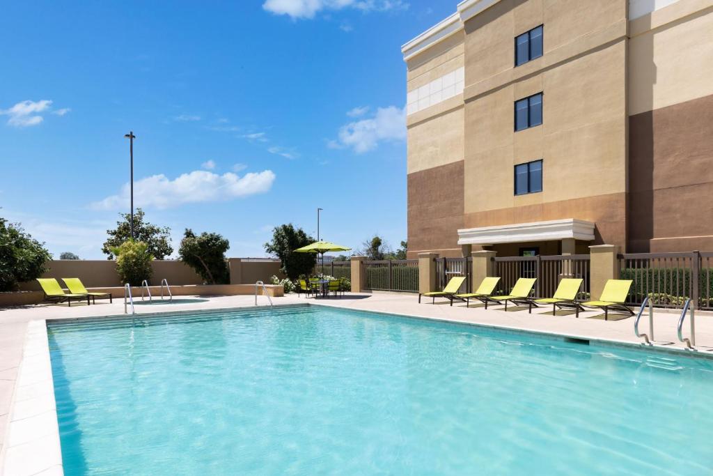 einem Pool vor einem Gebäude mit gelben Stühlen in der Unterkunft SpringHill Suites Fresno in Fresno