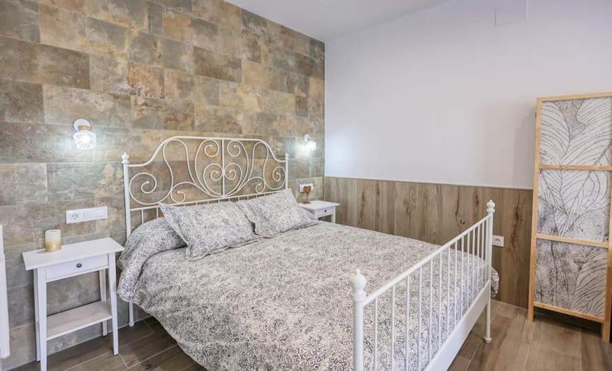 - une chambre avec un lit blanc et un mur en pierre dans l'établissement APARTAMENTO AMARÉ, à Conil de la Frontera