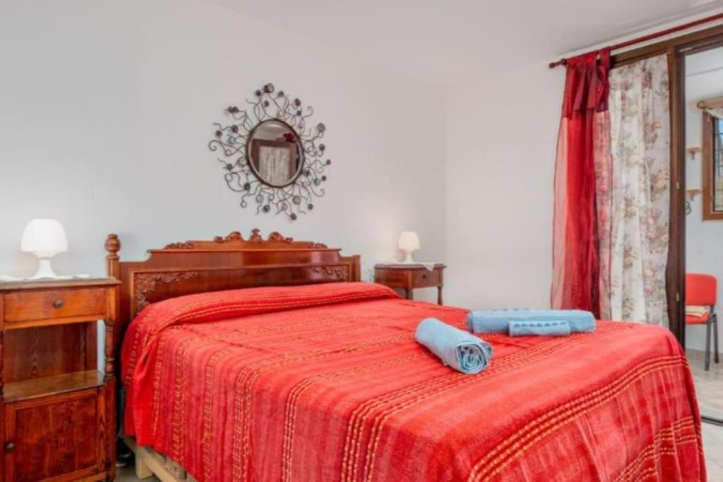 a bedroom with a bed with a red blanket and a mirror at La dolce dimora in Olbia