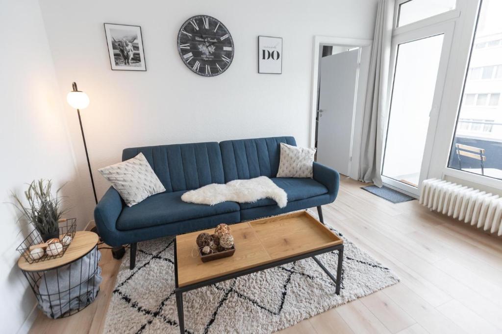 ein Wohnzimmer mit einem blauen Sofa und einem Tisch in der Unterkunft Koje Sieben I Apartment im Zentrum mit Meerblick in Bremerhaven