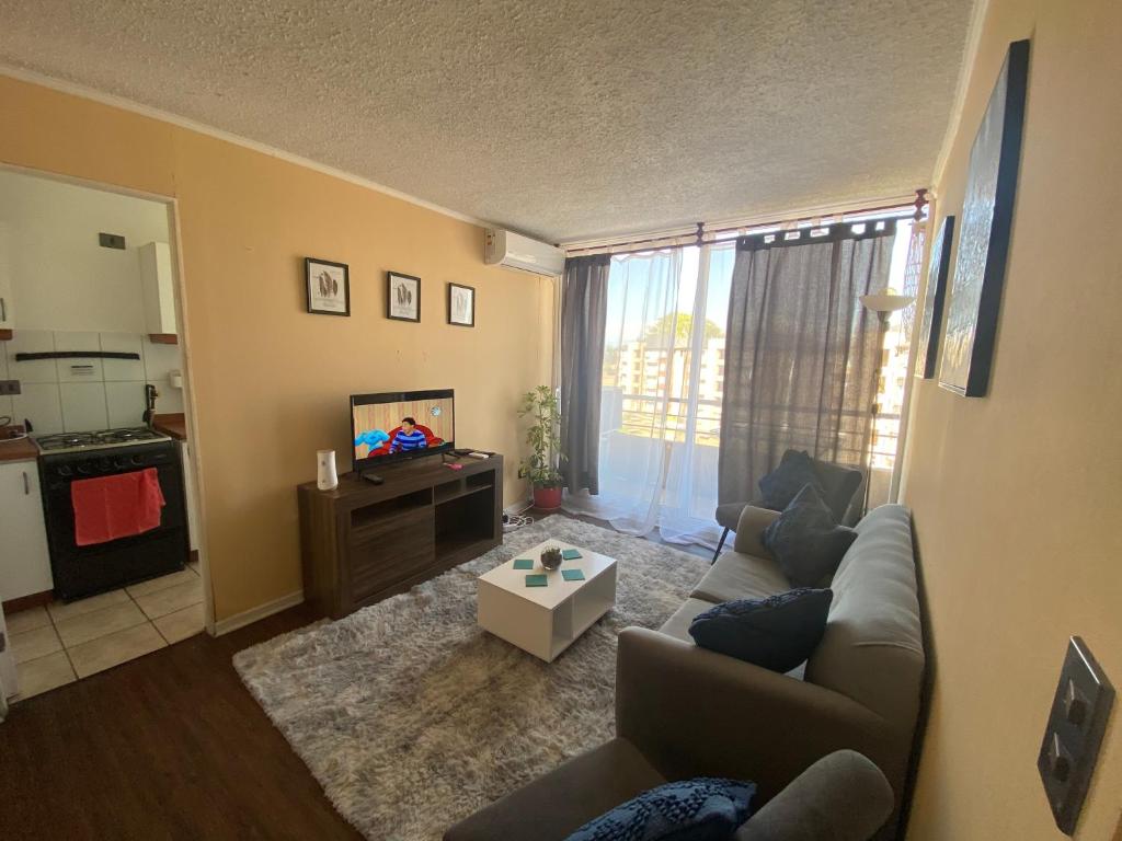 ein Wohnzimmer mit einem Sofa und einem TV in der Unterkunft Departamento familiar in Curicó