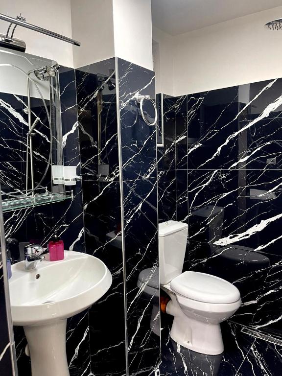 Baño en blanco y negro con aseo y lavamanos en Guest House Dashi, en Gjirokastra