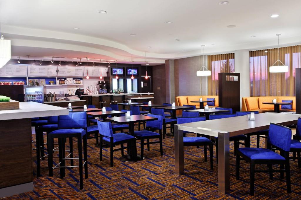a dining room with tables and blue chairs at Courtyard by Marriott Knoxville Airport Alcoa in Alcoa