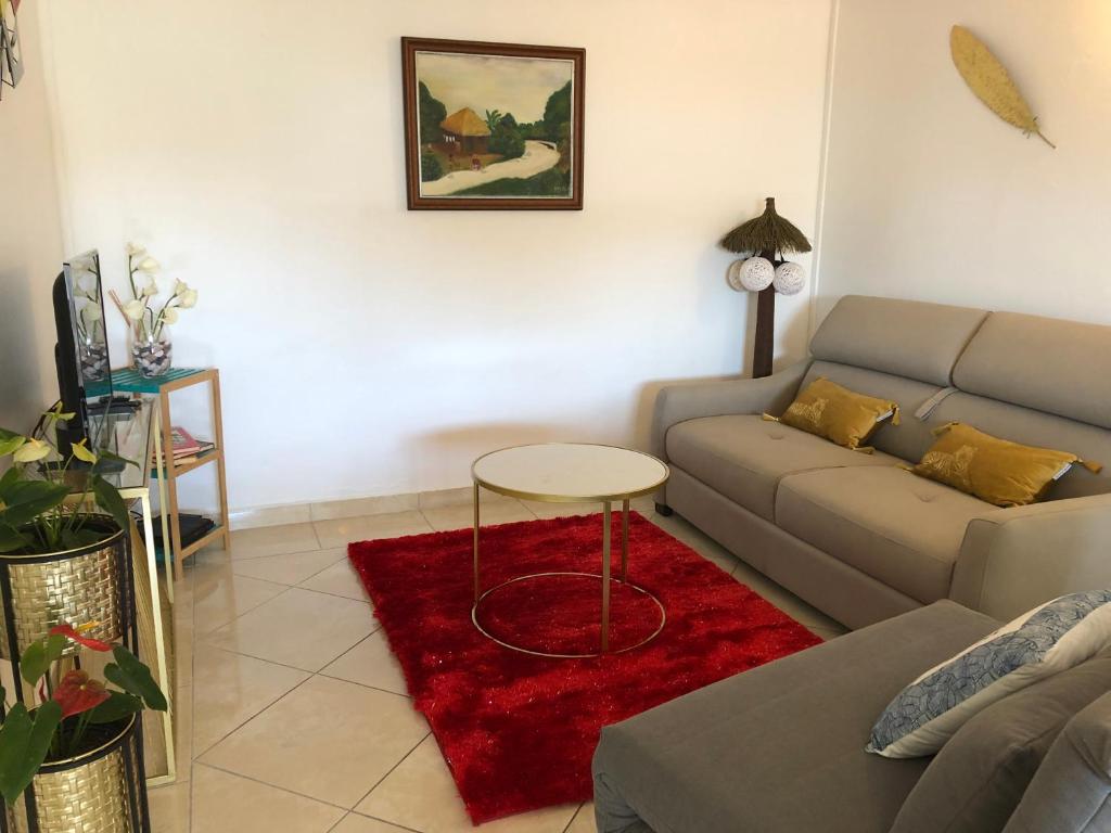 - un salon avec un canapé et un tapis rouge dans l'établissement Chez Laurenn, à Le Carbet