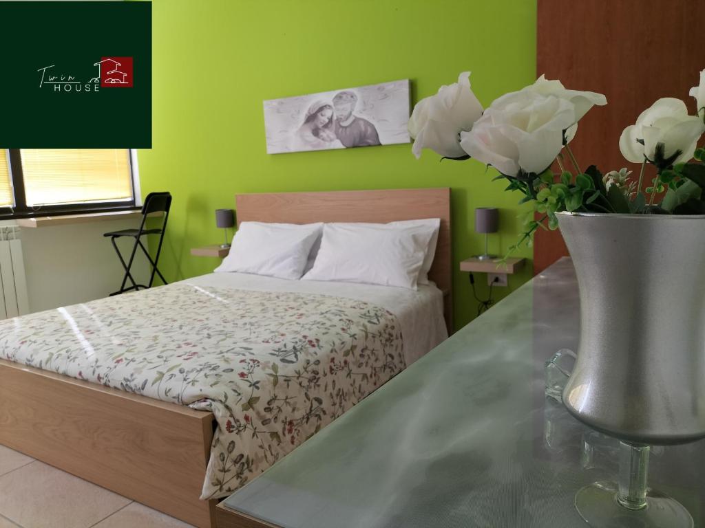 1 dormitorio con 1 cama y un jarrón de flores en TWIN HOUSE en Tito