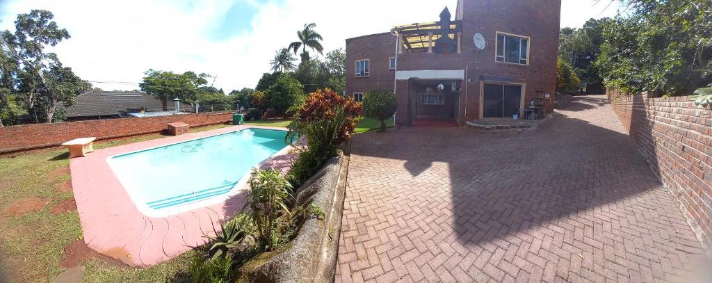 a swimming pool in front of a house at Rilli's Inn Studio in Mtunzini