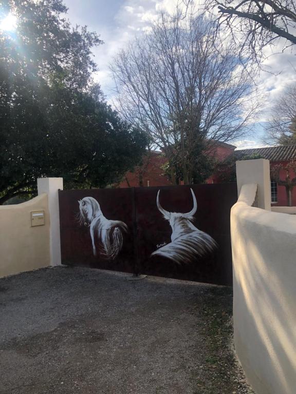 uma cerca com dois touros pintados nela em gite Au Bout du Chemin em Le Pouget