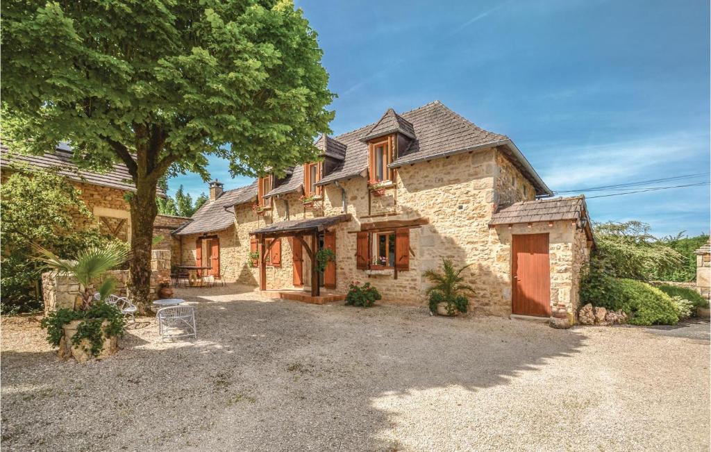 een groot stenen huis met een boom ervoor bij 3 Bedroom Awesome Home In Terrasspn-lavilledieu in Bouillac