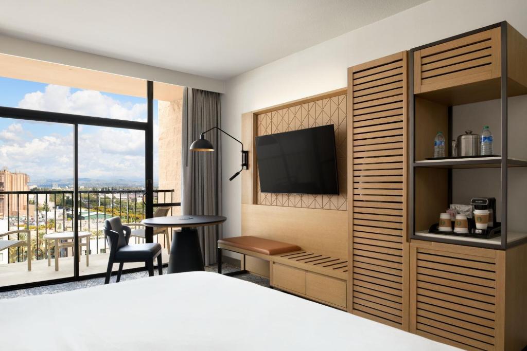 a bedroom with a bed and a television and a desk at Sheraton Park Hotel at the Anaheim Resort in Anaheim
