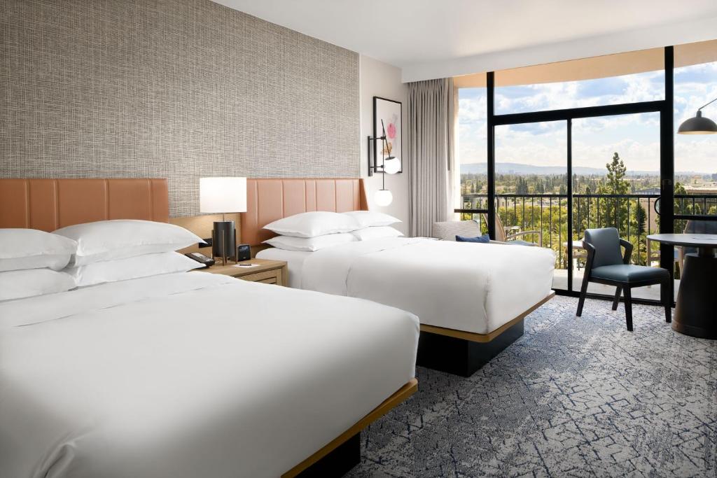 a hotel room with two beds and a balcony at Sheraton Park Hotel at the Anaheim Resort in Anaheim