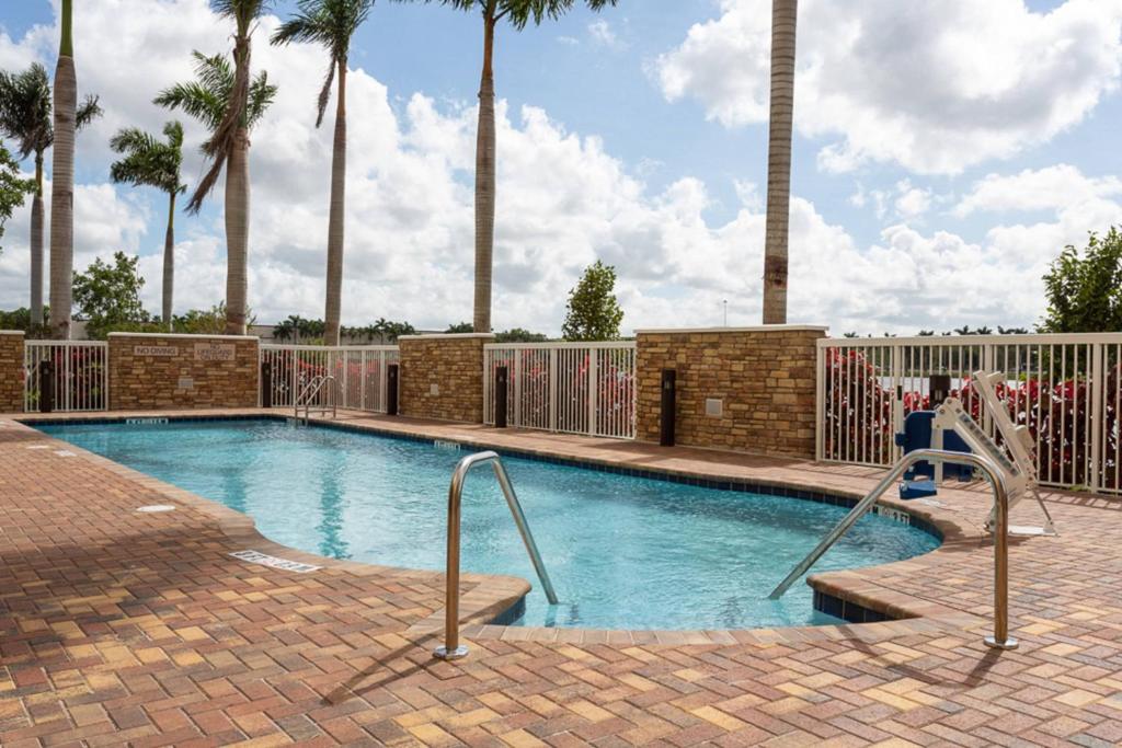 a swimming pool with palm trees in the background at SpringHill Suites by Marriott Fort Lauderdale Miramar in Miramar