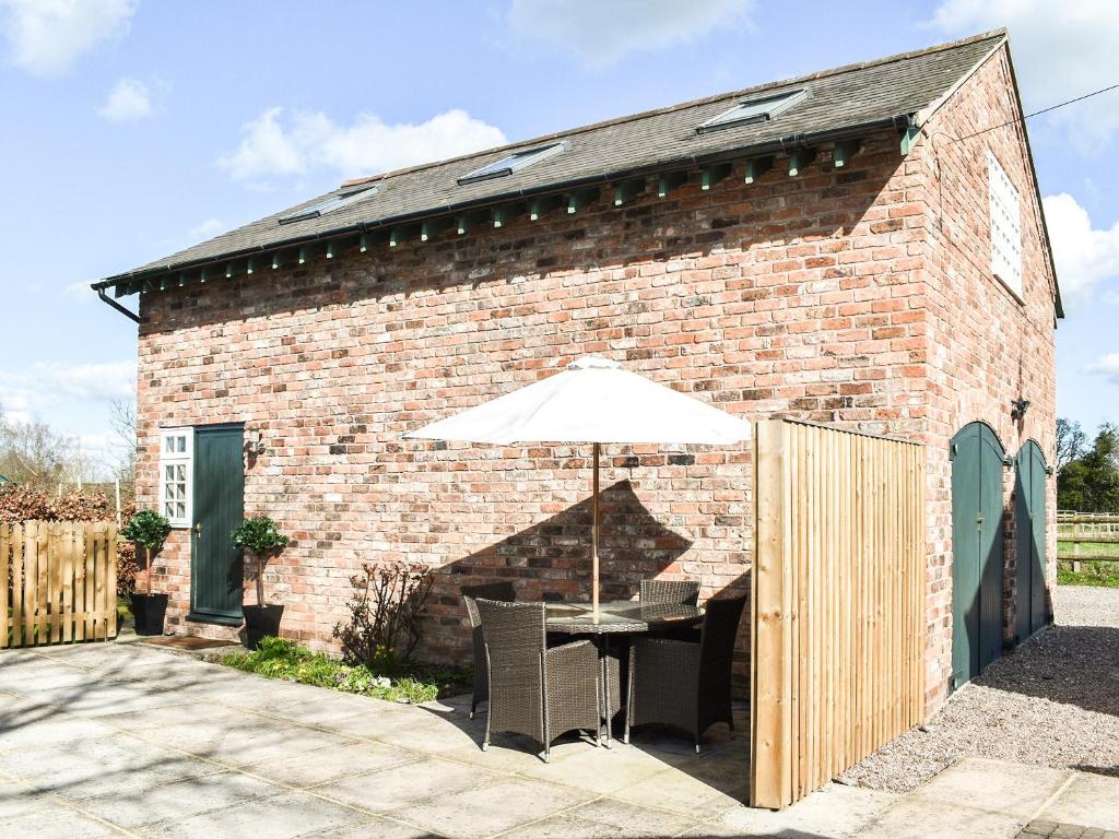 a brick building with a table and an umbrella at Elm House Studio in Christleton